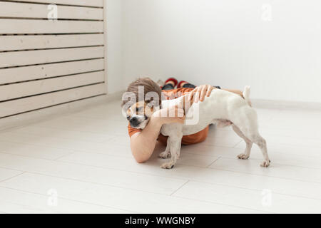 Menschen, Haustiere und Hunde Konzept - junge Mann umarmen funny Jack Russell Terrier auf weißen Raum Hintergrund Stockfoto