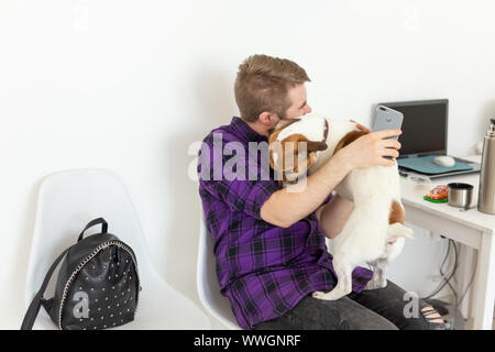 Menschen, Haustiere und Tiere Konzept - junge Mann umarmt Jack Russell Terrier und versuchen zu arbeiten Stockfoto