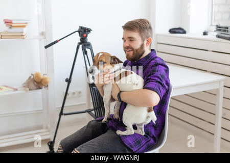 Menschen, Haustiere und Tiere Konzept - junge Mann umarmt Jack Russell Terrier und versuchen zu arbeiten Stockfoto