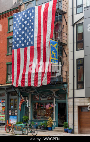 Eine gigantische Sterne und Streifen Flagge Vorhänge über dem Feuer auf der Vorderseite der Flaggen & des Humphry Banner Shop mit 238 Arch St, die Termine von 1864 Stockfoto