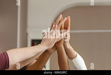 Gruppe von multi-ethnische Schüler heben die Hände zusammen Stockfoto