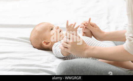 Mutter massierte Süßes neugeborenes Baby, Übungen für seine Entwicklung. Stockfoto