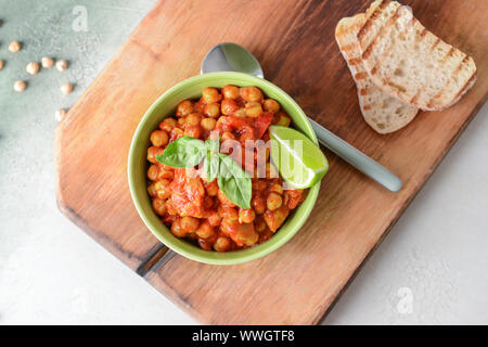 Schüssel mit leckerem Kichererbse in Tomatensauce auf Tisch Stockfoto