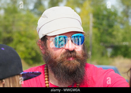 Samara, Russland - 17. August 2019: Portrait eines unbekannten Mann in Sonnenbrille, mit Bart, in einem roten T-Shirt und Cap Stockfoto