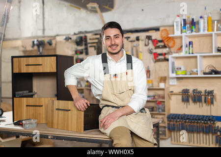 Möbelfabrik, kleines Unternehmen und Personen Konzept - Porträt eines lächelnden männlichen Arbeitnehmer bei der Herstellung Stockfoto