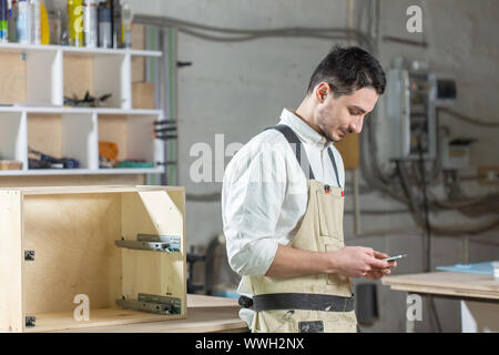 Möbelfabrik, kleines Unternehmen und Personen Konzept - junge Arbeitnehmer arbeitet in einer Fabrik für die Herstellung von Möbeln Stockfoto