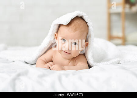 Adorable Baby boy Kriechen auf Bett und versteckt unter Vertrag Stockfoto