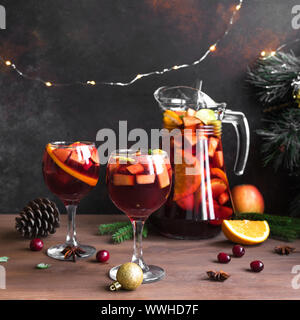 Weihnachten Sangria oder Punch in Gläser und Krug. Hausgemachten Rotwein Obst Sangria und Weihnachten festliches Dekor auf Holz- Hintergrund, kopieren. Stockfoto