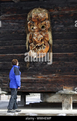 Frau sieht großen traditionellen hölzernen Maske aus Kiefernholz Stockfoto