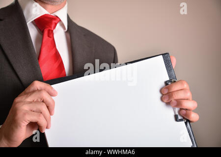 Mann in Anzug mit roter Krawatte mit einem Ordner mit leeren Blätter mit braunen isolierten Hintergrund. Horizontale Komposition. Vorderansicht. Stockfoto