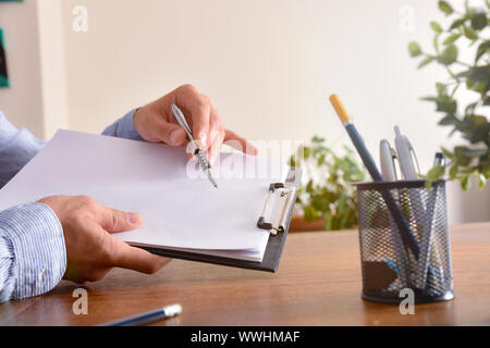 Mann zeigt leeres Blatt Papier in einem Ordner sitzt vor einem Tisch.. Horizontale Komposition. Von der Seite. Stockfoto