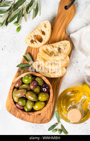 Oliven, Ciabatta und Olivenöl auf weißem Hintergrund. Stockfoto