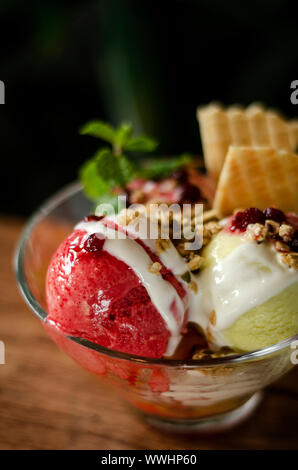 Erdbeeren und Pistazien Eis Eisbecher Dessert in Schale auf Holztisch Stockfoto