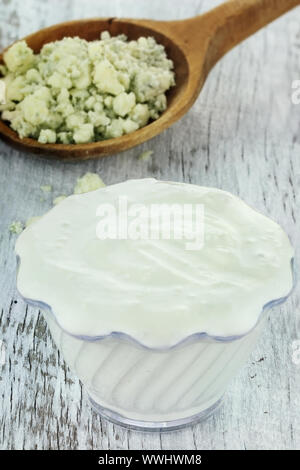 Schüssel mit frisch zubereiteten Blau Käse Salat Dressing mit Klumpen des blauen Käse in Löffel aus Holz auf einem urigen Hintergrund. Stockfoto