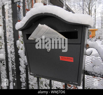 Verschneite Briefkasten mit der Sonntagszeitung Stockfoto