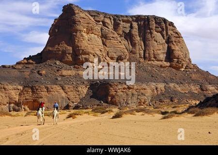 Touristen reiten auf Kamelen in ein Wadi der Sahara Stockfoto