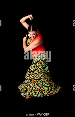 Schönen Spanischen kaukasischen Flamenco, Paso Doble Tänzer trägt einen bunten Rock mit Polka Dots und orangefarbenen T-shirt Tun einer Linie darstellen, auf Bl isoliert Stockfoto