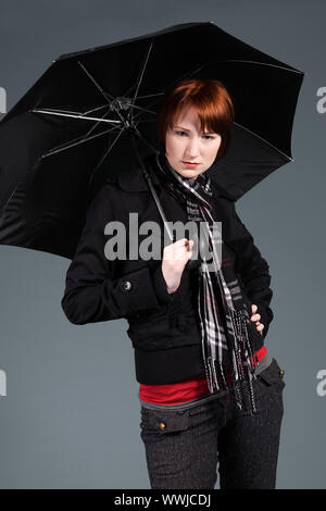 Junge rothaarige Mädchen mit ihrem Schirm Stockfoto