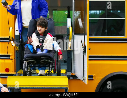 Behinderte fünf Jahre alten Jungen mit einem Bus Lift für seinen Rollstuhl Stockfoto