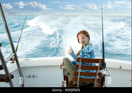 Fischerin Big Game auf dem Boot Stuhl ok Zeichen glücklich Stockfoto