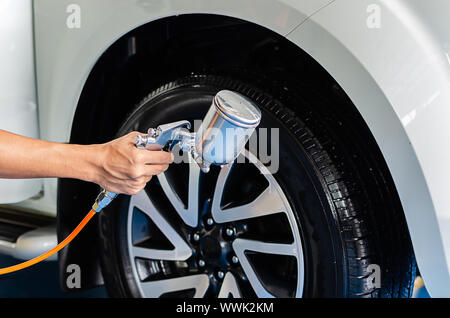 Sprühen Sie die Reifen nach dem Waschen, mit dem Auto die Reifen glänzend und schwarz zu machen. Stockfoto