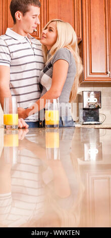 Junges Paar Lächeln einander mit Gläser Orangensaft auf Zähler. Vertikale erschossen. Stockfoto