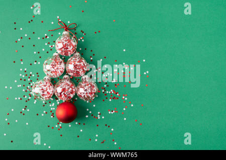 Glas Weihnachtskugeln mit Stern glitter Inside in der Form eines Weihnachtsbaumes auf grünem Hintergrund angeordnet. Flach Stockfoto