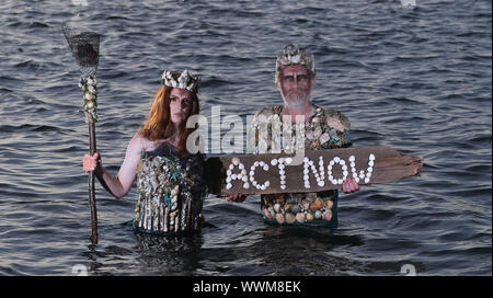 Ceara Carney, und Louis Heath, des Aussterbens Rebellion Irland, gekleidet als â €˜Meer godsâ €™, in Killiney Bay Dublin, als Aktivisten haben gefordert, die irische Regierung drehen das Blatt auf ihre Bewerbung, um den Klimawandel anzugehen. Stockfoto