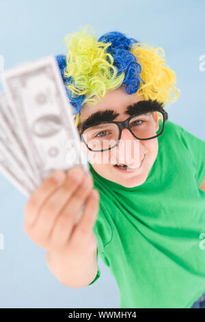 Jungen tragen Clown Perücke und falsche Nase halten Geld Stockfoto