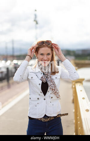 Glückliche junge trendige stilvolle urbane Frau Sonnenbrille entfernen im Herbst Stockfoto