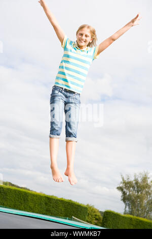 Junges Mädchen springen auf dem Trampolin lächelnd Stockfoto
