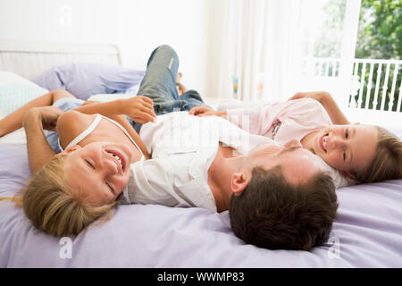 Mann mit zwei jungen Mädchen lächelnd im Bett liegend Stockfoto