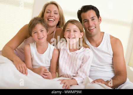 Familie sitzt im Bett lächelnd Stockfoto