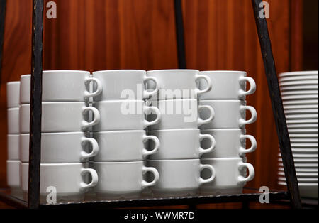 Stapel von sauberen weißen Keramikbechern in einer Restaurantküche Stockfoto