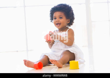 Baby drinnen spielen mit Cup-Spielzeug Stockfoto