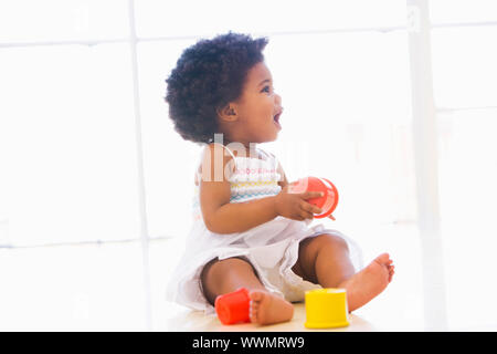 Baby drinnen spielen mit Cup-Spielzeug Stockfoto