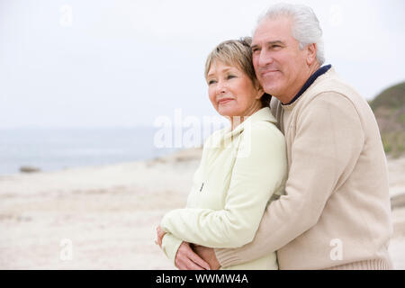 Paar am Strand umarmen und lächelnd Stockfoto