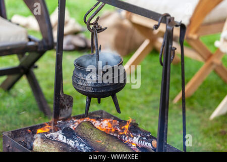 Rostigen Kochtopf simmering über offenem Feuer auf einem Campingplatz. Stockfoto