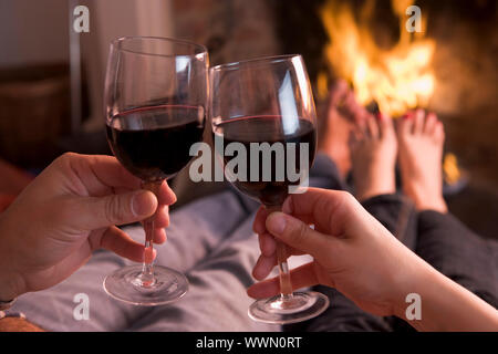 Füße mit Händen mit Wein am Kamin Erwärmung Stockfoto