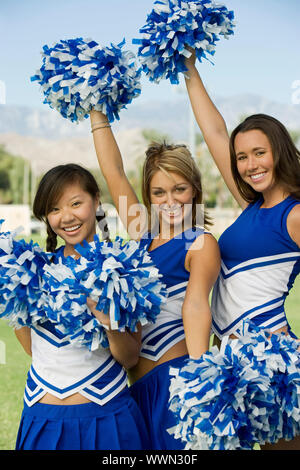 Cheerleadern in Uniform Holding Pom-Poms Stockfoto