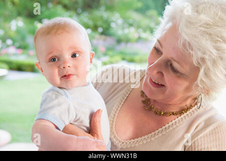 Großmutter im Freien auf der Terrasse mit Baby Lächeln Stockfoto