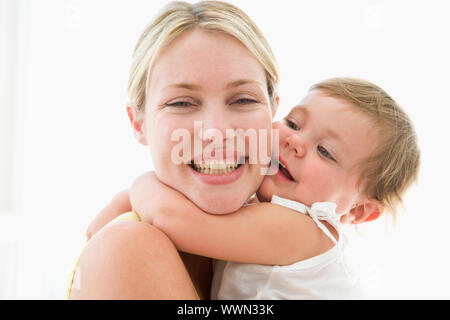 Mutter und Baby drinnen umarmt und lächelnd Stockfoto
