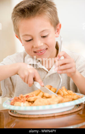 Kleiner Junge drinnen essen Fish &amp; Chips lächelnd Stockfoto