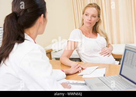 Arzt mit Laptop und Schwangere in Arztpraxis Stockfoto