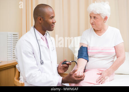 Arzt überprüft Frau Blutdruck im Prüfungsraum Stockfoto