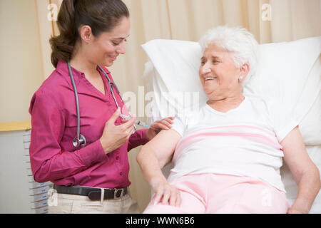 Arzt Frau in Exam Room lächelnd Nadel verleihen Stockfoto