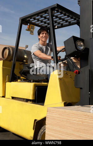 Gabelstapler Fahrer auf Gabelstapler mit Stapel von Holz Stockfoto