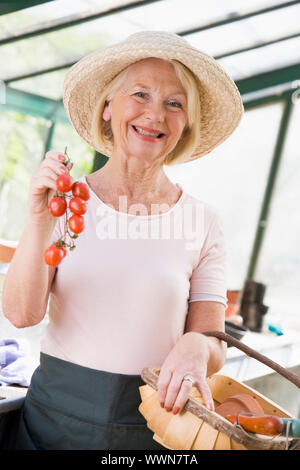 Frau im Gewächshaus halten lächelnd Cherry-Tomaten Stockfoto