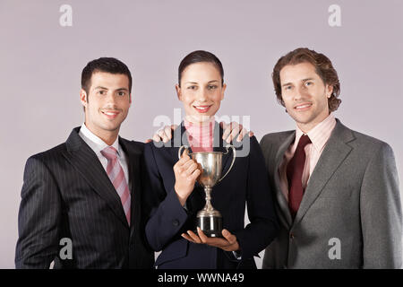 Geschäftsfrau und Geschäftsleute halten Trophy Stockfoto