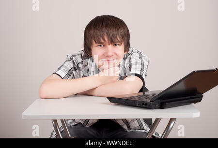 Schüler störte zu erlernen, er sitzt am Tisch, auf dem steht der Computer Stockfoto